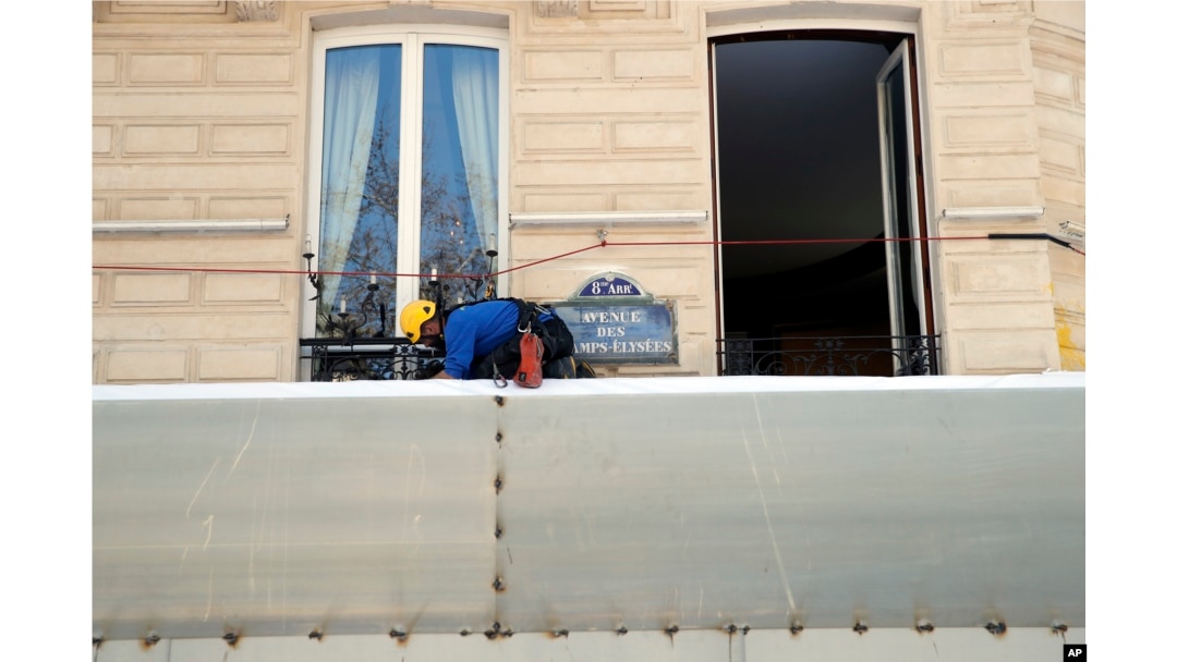 A worker sets up protections on the famed restaurant Fouquet's of the Champs-Elysees, in Paris, March 22, 2019. French President Emmanuel Macron announced that soldiers would be deployed across the country to help maintain security during "yellow vest" protests.