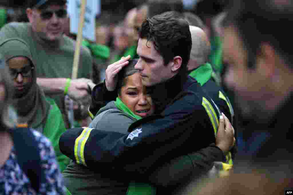 A woman hugs a fire-fighter as members of the public take part in a silent march as part of commemorations on the first anniversary of the Grenfell fire in west London, England.