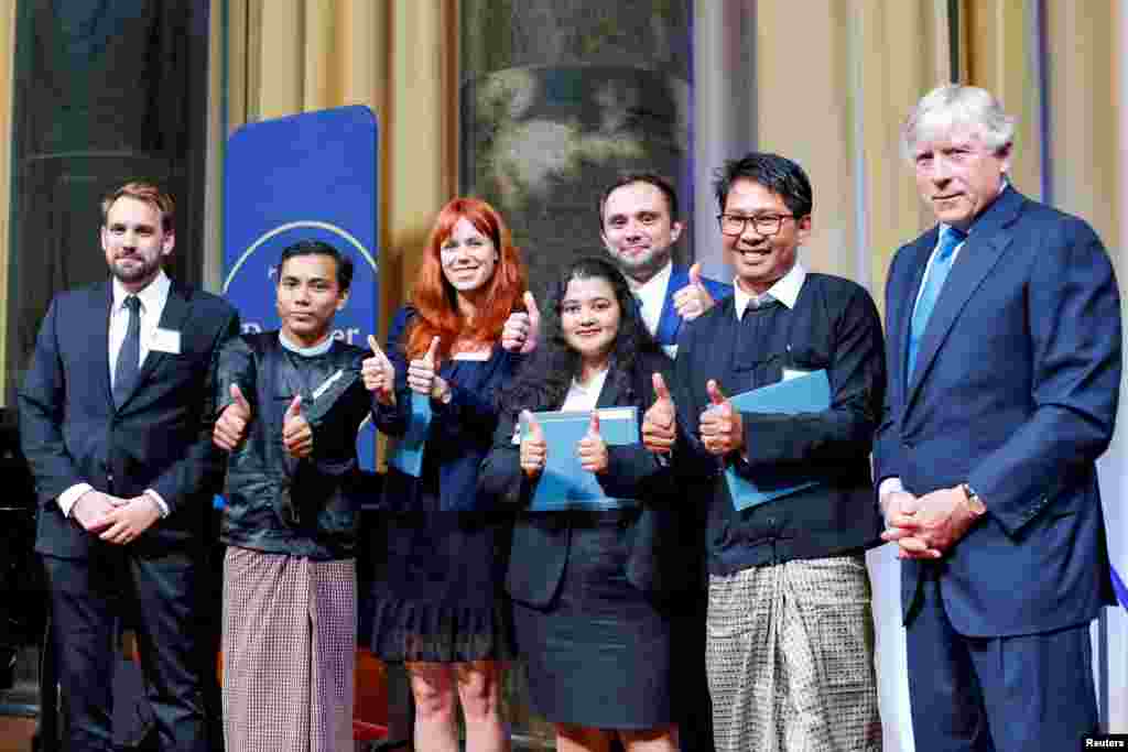 From left to right: Reuters Pulitzer winners for International Reporting Simon Lews, Kyaw Soe Oo, Poppy McPherson, Shoon Naing, Anthony Slodkoski, Wa Lone, and Columbia University president Lee Bollinger pose for a picture inside Low Library at Columbia University in New York, May 28, 2019.