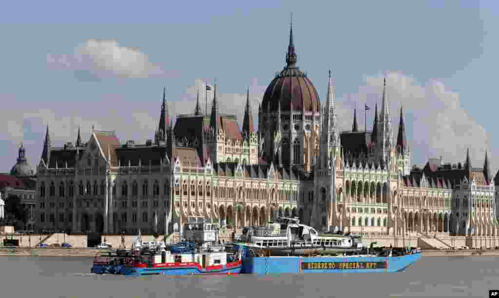 A barge carries the sightseeing boat, right, past the house of parliament on the Danube river after it was lifted from riverbed in Budapest, Hungary. Four people are still missing from the May 29 collision between the Hableany (Mermaid) sightseeing boat and the Viking Sigyn river cruise ship near to Budapest's Margit Bridge.
