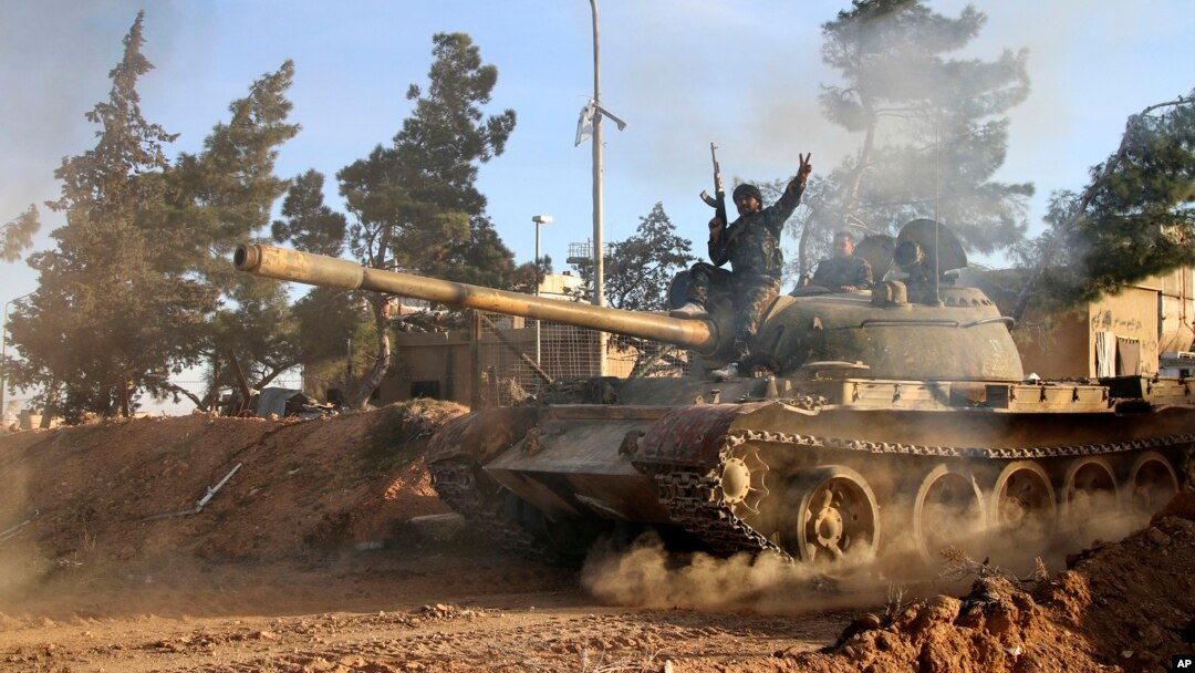 FILE - А volunteer fighter with Syrian government forces sits atop a tank in the province of Raqqa, Syria, Feb. 17, 2016. Backed by Russia and Iran, Syrian forces seen as much better positioned than the U.S.-led coalition and its regional allies to take 