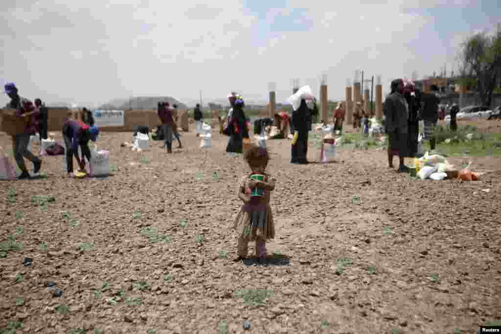 A girl carries food aid she received from the local charity, Mona Relief, ahead of the holy month of Ramadan on the outskirts of Sana'a, Yemen.