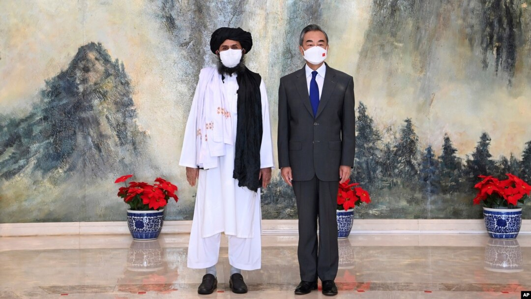 In this photo released by China's Xinhua News Agency, Taliban co-founder Mullah Abdul Ghani Baradar, left, and Chinese Foreign Minister Wang Yi pose for a photo during their meeting in Tianjin, China, July 28, 2021.