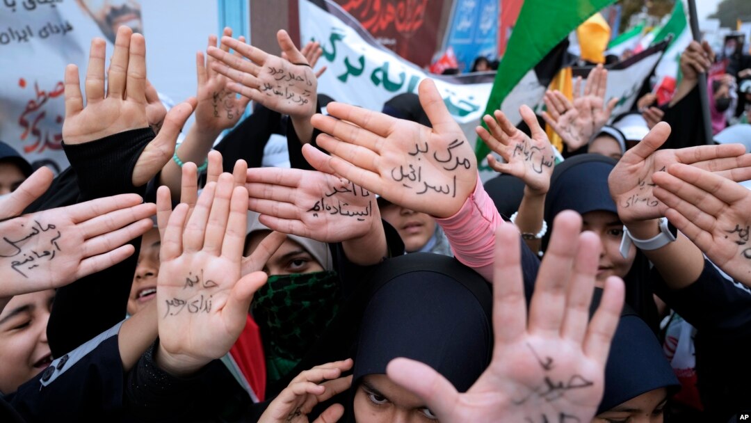 Iranian schoolgirls show their hands with pro-government slogans and an anti-Israeli slogan that reads in Farsi: "Death to Israel," during a rally in front of the former U.S. Embassy in Tehran, Iran, on Nov. 4, 2023.
