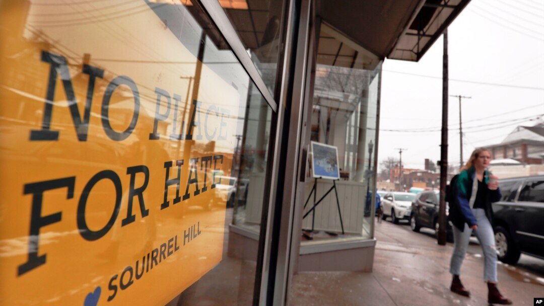 FILE - A woman passes by a "No Place For Hate" sign in a shop in Pittsburgh's Squirrel Hill neighborhood, Feb. 11, 2019.