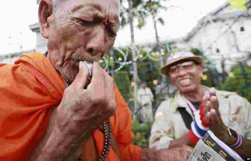 A Buddhist monk blows a whistle during a rally outside Interior Ministry in Bangkok, Nov. 26, 2013.