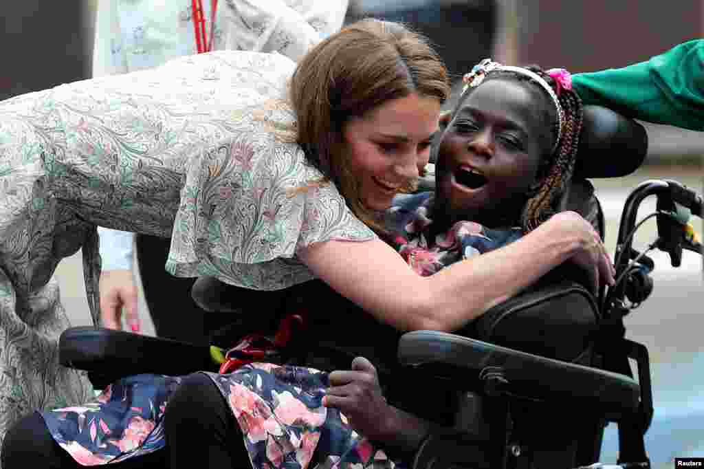 Britain's Catherine, Duchess of Cambridge, hugs a girl in a wheelchair as she joins a photography workshop with Action for Children in Kingston upon Thames.