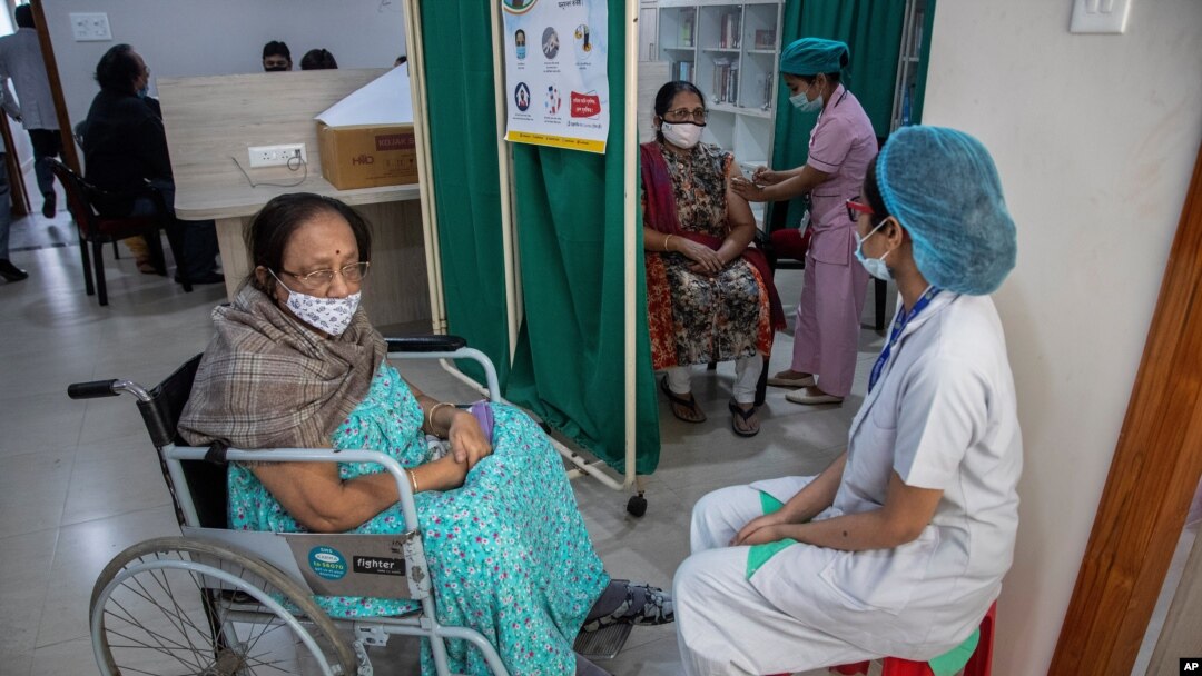 A woman receives the COVID-19 vaccine as another waits in a wheelchair at a private hospital in Gauhati, India, March 4, 2021.