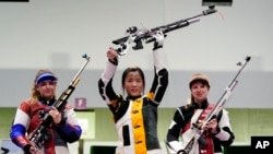 中國選手楊倩在女子10米氣步槍的比賽中摘取本屆奧運會首枚金牌後將步槍舉起（2021年7月24日）