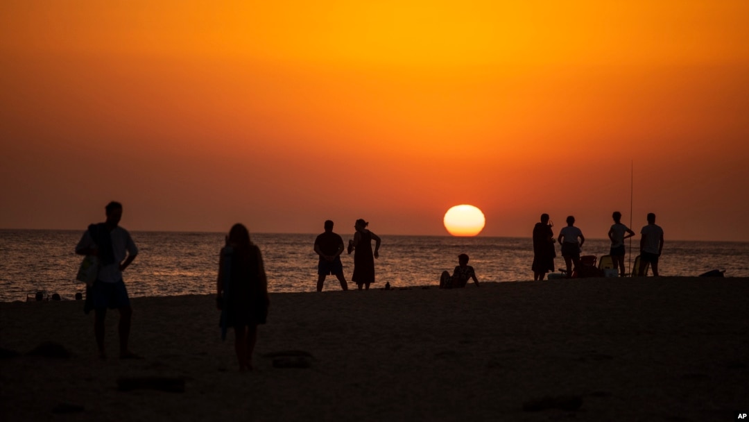 ARCHIVO: Personas observan el atardecer en una playa cerca del faro de Trafalgar, el 29 de julio de 2020, en Los Caños de Meca, España. 