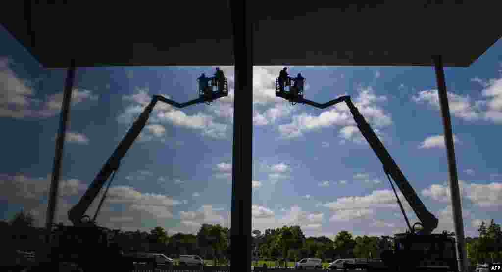 Workers on a mobile crane are reflected in the glass facade of the Paul-Loebe-Haus parliamentary annex amid preparations to host the swearing-in ceremony of Germany's new defense minister on July 24, 2019.