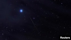 FILE - A meteor of the Orionid meteor shower, created by remnants of Halley's Comet, streak through the night sky past Halley's Comet, above the San Rafael Swell outside Green River, Utah, Oct. 23, 2019. 