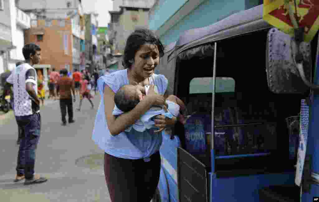 A woman living near St. Anthony's shrine runs for safety with her infant after police found explosive devices in a parked vehicle in Colombo, Sri Lanka.