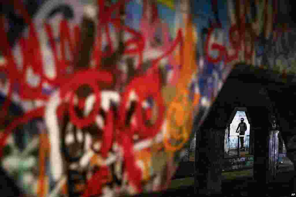 A person rides a scooter through Atlanta's Krog Street Tunnel, which runs under train tracks carrying freight cars and is known for its urban street art, Atlanta, Georgia.
