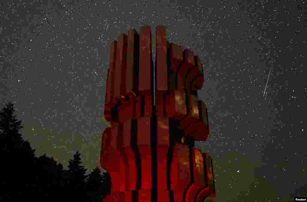 A meteor streaks across the sky near the Monument to the Revolution at Kozara during the peak of the Perseid meteor shower in Prijedor, Bosnia and Herzegovina.