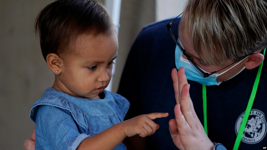 El voluntario Mark McDonald, a la derecha, trabaja con un niño inmigrante en una clínica habilitada para solicitantes de asilo que esperan en Matamoros, México, el jueves 19 de noviembre de 2020.
