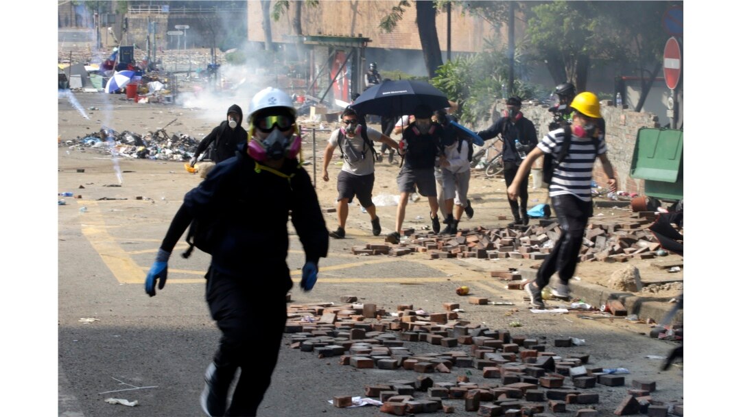 Protesters run as police fire tear gas near Hong Kong Polytechnic University in Hong Kong, Monday, Nov. 18, 2019.