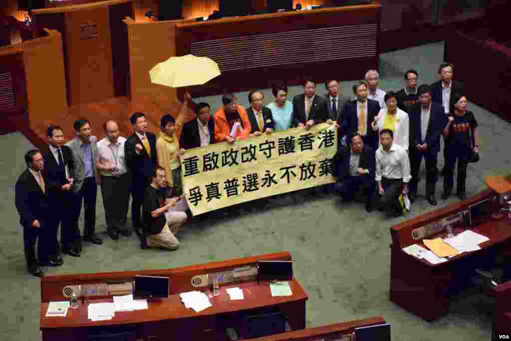 20多位泛民主派立法會議員在港府政改方案被否決後,到會議廳內主席台前展示標語。(美國之音 湯惠芸攝)