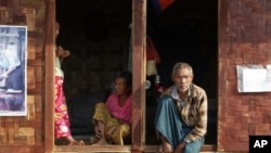 Ethnic Kachin people sit in the doorways of shelters at a temporary camp for people displaced by fighting between government troops and the Kachin Independence Army, or KIA, outside the city of Myitkyina in the north of the country, February 22, 2012.
