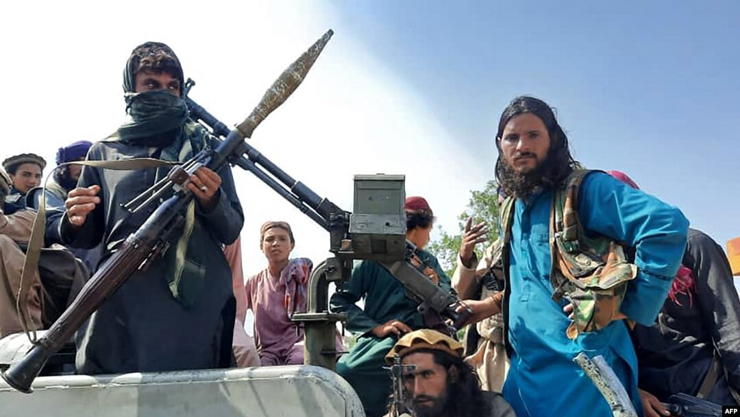 Taliban fighters sit over a vehicle on a street in Laghman province on August 15, 2021. 