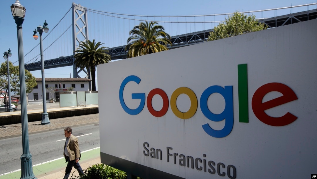  man walks past a Google sign outside with a span of the Bay Bridge at rear in San Francisco, May 1, 2019.