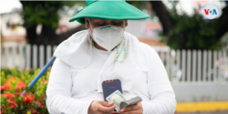 Personas dedicadas al cambio de dólares, conocidos como "cambistas", se cubren la cara para protegerse del coronavirus en las calles de Managua, Nicaragua. Agosoto de 2021. [Fotografía: Houston Castillo Vado]