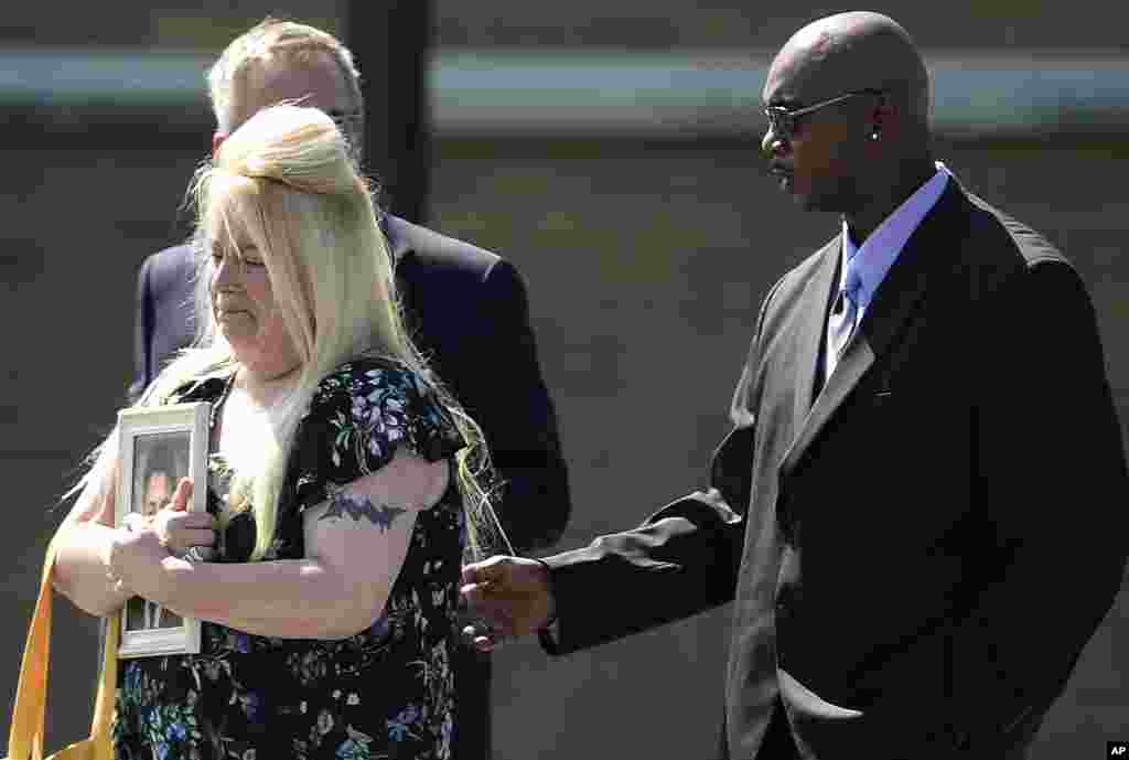Tammy Williams, left, holds a photo of her son Trevor Irby, 25, as she and her husband Will leave a funeral service in Romulus, New York. Irby and two others were killed on July 28 when Santino William Legan cut through a fence and opened fire with a Romanian-made AK-47 style-rifle at the popular Gilroy Garlic Festival.
