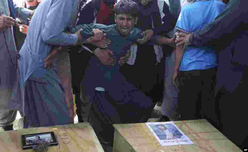 A relative wails near the coffins of victims of the Dubai City wedding hall bombing during a mass funeral in Kabul, Afghanistan. The Islamic State group's Afghan branch claimed responsibility for the wedding bombing that killed at least 63 and wounded at least 183.