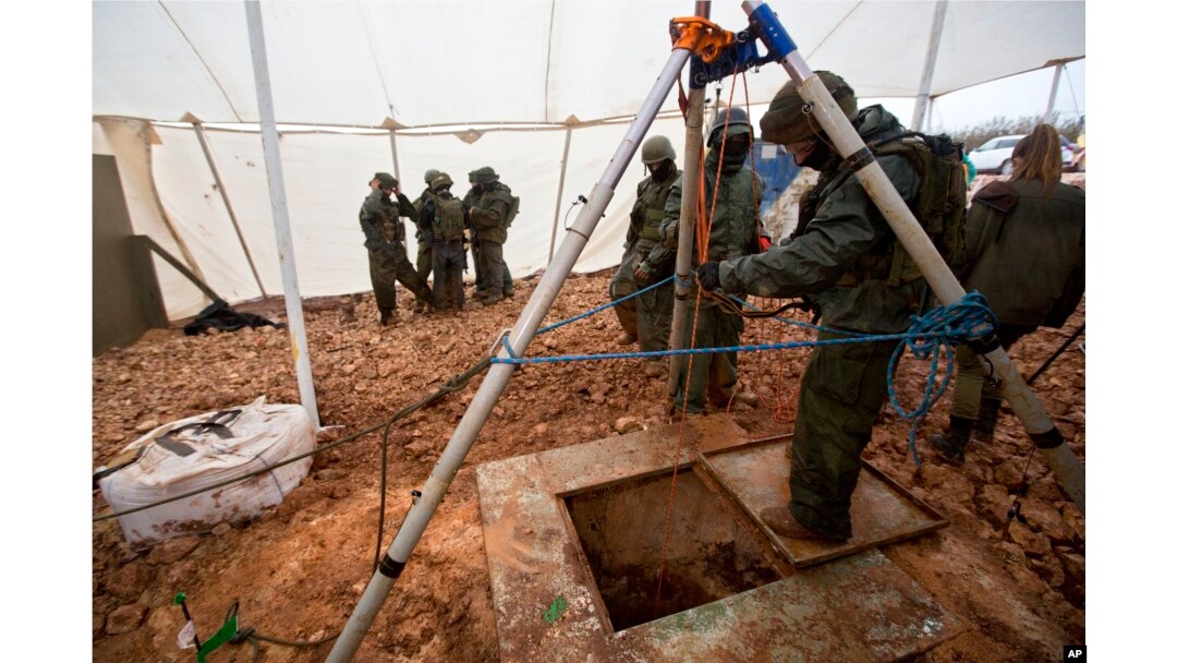 FILE - Israeli soldiers stand around the opening of a hole that leads to a tunnel that the army says crosses from Lebanon to Israel, near Metula, Dec. 19, 2018.