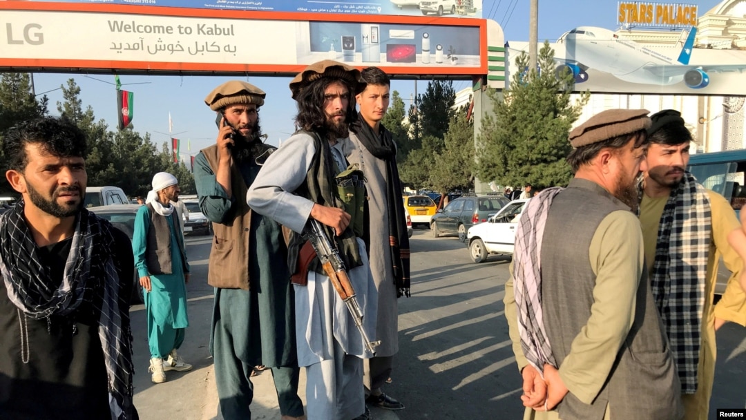 A member of Taliban, center, stands outside Hamid Karzai International Airport in Kabul, Afghanistan, August 16, 2021. 