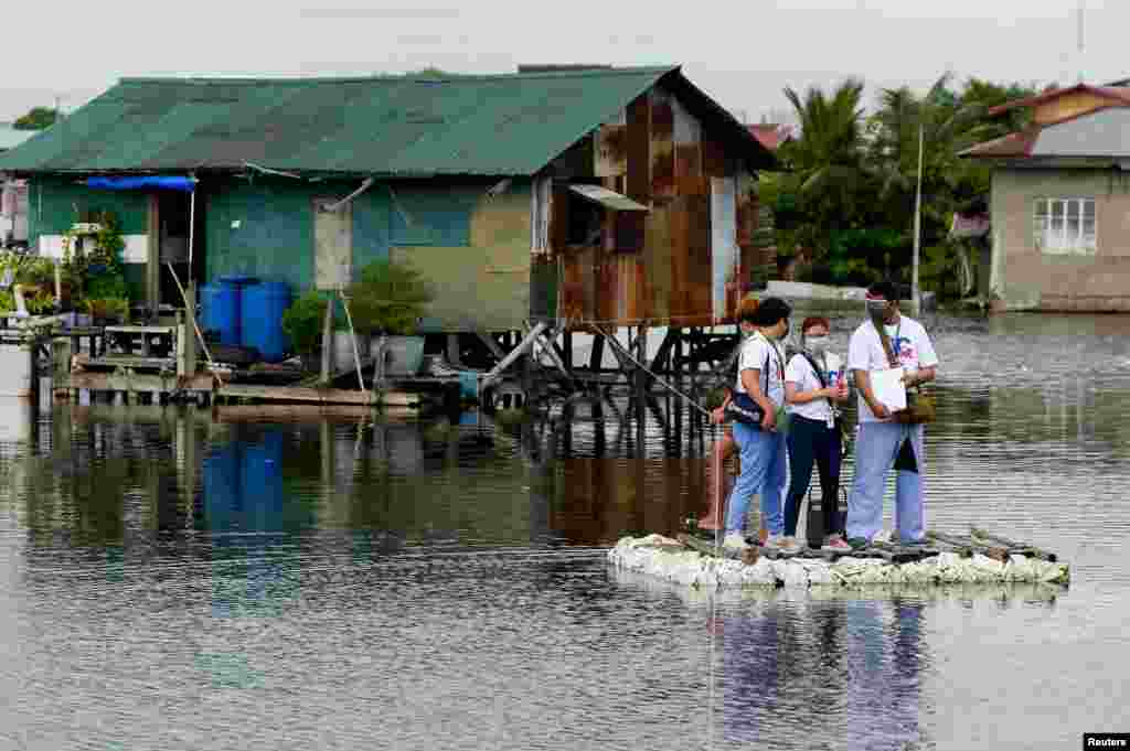 Health care workers ride on a makeshift raft during the house to house vaccination of bedridden citizens for the coronavirus disease, in Valenzuela City, Metro Manila, Philippines.