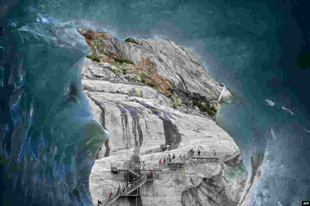People walk on footbridges as they visit 'La Grotte de Glace' (Ice cave) on France's largest glacier, 'Mer de Glace' (Sea of Ice), in Chamonix-Mont-Blanc, in the French Alps, eastern France.