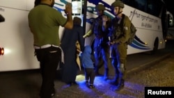 ISRAEL - People walk past Israeli soldiers as they board a bus during the Syria Civil Defence, also known as the White Helmets, extraction from the Golan Heights, Israel in this still image taken from video, provided by the Israeli Army July 22, 2018.
