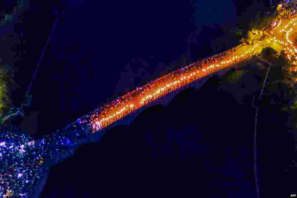 People walk on a bridge with torches as they celebrate the torch festival in Bijie, China's southwestern Guizhou province, July 29, 2019.