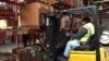Ex-offender Wade Tate drives a forklift for DSI Warehouse in greater Memphis, Tenn. His boss says customers ask to meet Tate in person to offer thanks for his computer assistance with their orders. (C. Presutti / VOA)
