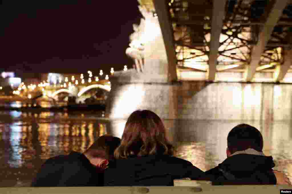 People sit under the Margaret Bridge near the site of a ship accident, which killed several people, on the Danube river in Budapest, Hungary.