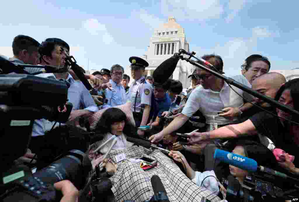 Wheelchair-bound Japanese lawmaker Eiko Kimura (C) is surrounded by the media upon her arrival at Parliament in Tokyo. Two lawmakers with serious paralysis took their seats in Japan's upper house, marking the first time people with severe disabilities have served in the body.