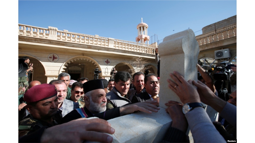 Iraqi Christians take part in a procession to erect a new cross over the Mar Korkeis church, after the original cross was destroyed by Islamic State militants, in the town of Bashiqa, Iraq, Nov. 19, 2016.