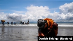 An exhausted Rohingya refugee woman touches the shore after crossing the Bangladesh-Myanmar border by boat through the Bay of Bengal, in Shah Porir Dwip, Bangladesh, on September 11, 2017. (Danish Siddiqui/Reuters)