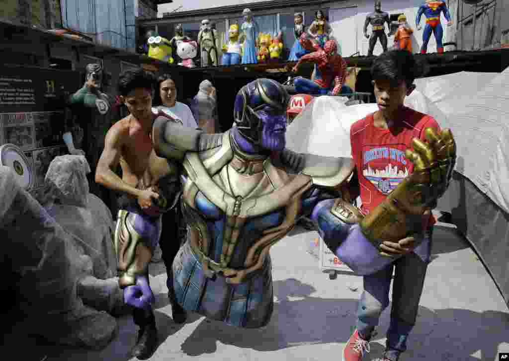 Workers carry a life-sized figure of Thanos, a character in the popular movie 'Avengers,' as they prepare to display it outside their shop in Manila, Philippines.