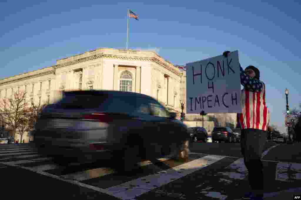 Mtu akiandamana nje ya bunge la Marekani Washington, DC Disemba 18, 2019 wakati baraza la Wawakilishi likijadili vifungu viwili vya kumfungulia mashtaka Rais Donald Trump. (Photo by Alex Edelman / AFP)
