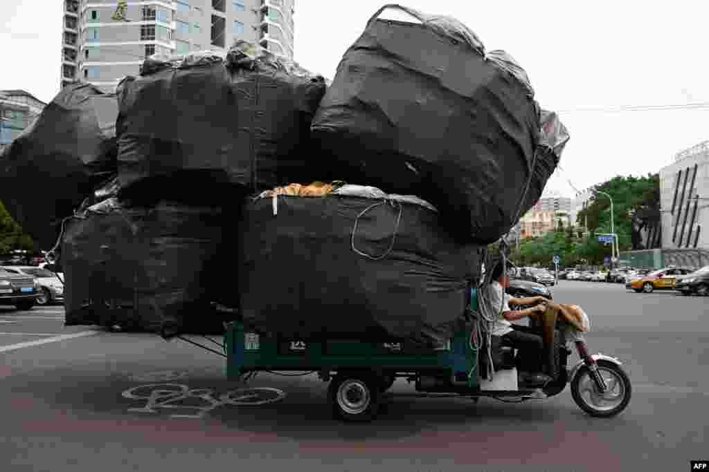 A man rides an electric tricycle loaded with goods on a street in Beijing, China.