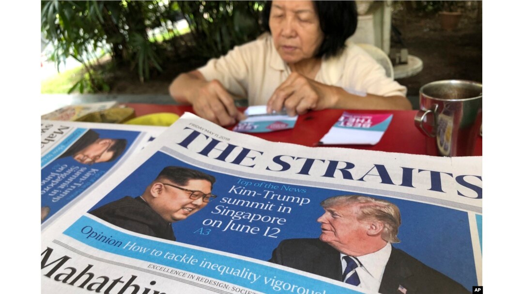 A news vendor counts her money near a stack of newspapers with a photo of U.S. President Donald Trump, right, and North Korea's leader Kim Jong Un on its front page on May 11, 2018, in Singapore.