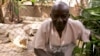 Burundian Albert Ngendera poses with his pets, eight crocodiles that will soon become over 40 and no longer fit on his porch. (VOA / H. McNeish)