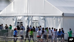 FILE - Detained migrant children from Central America line up to enter a tent at the Homestead Temporary Shelter for Unaccompanied Children in Homestead, Florida, Feb. 19, 2019.
