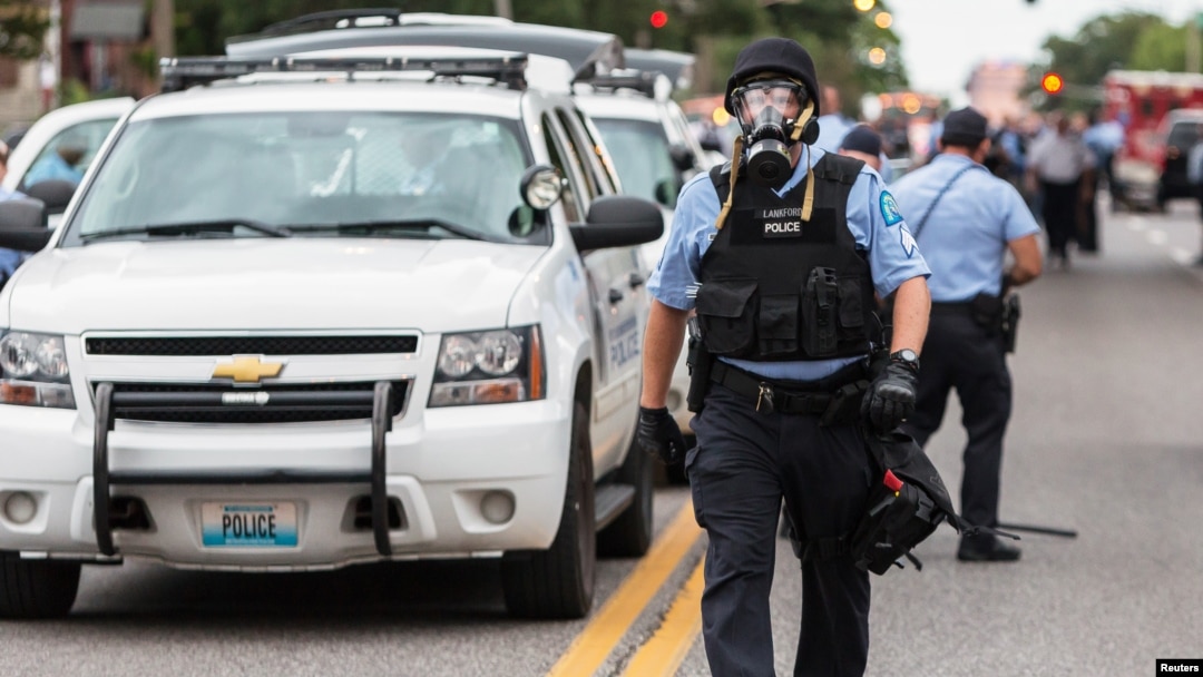 FILE - Police wear gas masks as they attempt to disperse a crowd that gathered after a shooting incident in St. Louis, Missouri August 19, 2015. 
