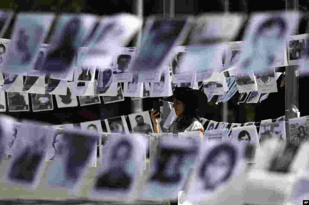 Framed by images of people who have been disappeared, a woman takes photos during a Mother's Day march in Mexico City, Mexico.