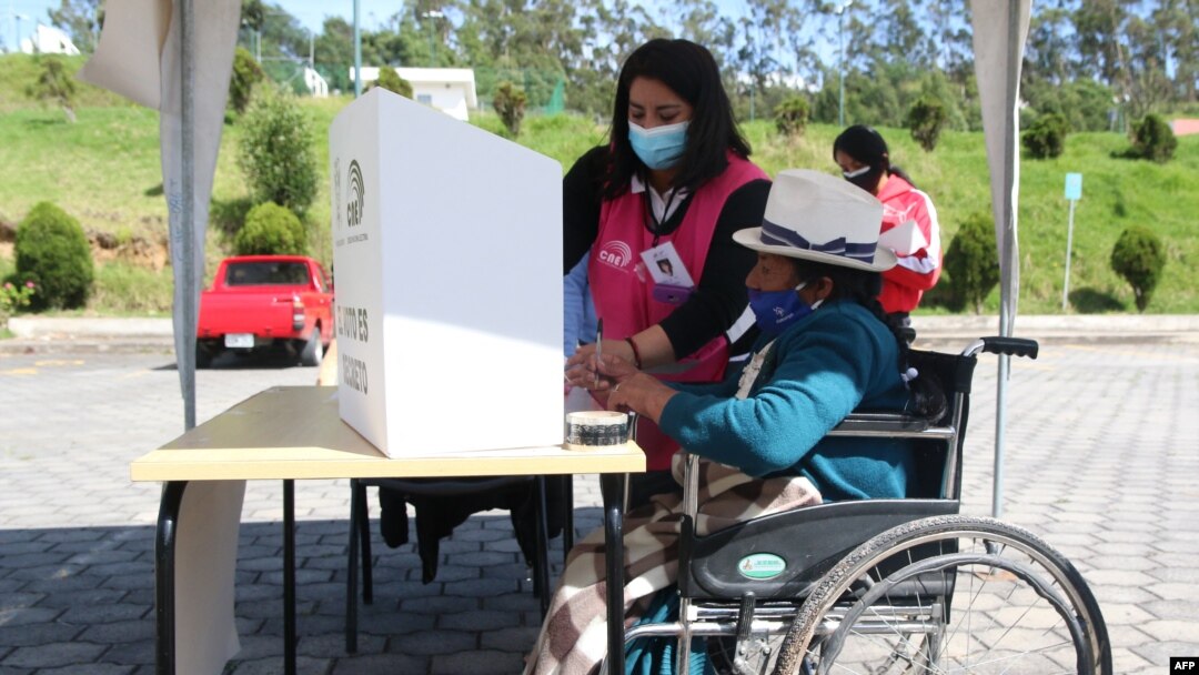 Una mujer indígena en silla de ruedas es asistida en un colegio electoral en Cuenca, Ecuador, el 11 de abril de 2021.