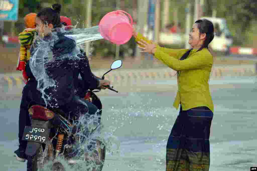 A woman throws water at passing motorists during celebrations for the Thingyan festival, also known as the Buddhist New Year, in Naypyidaw, Myanmar.