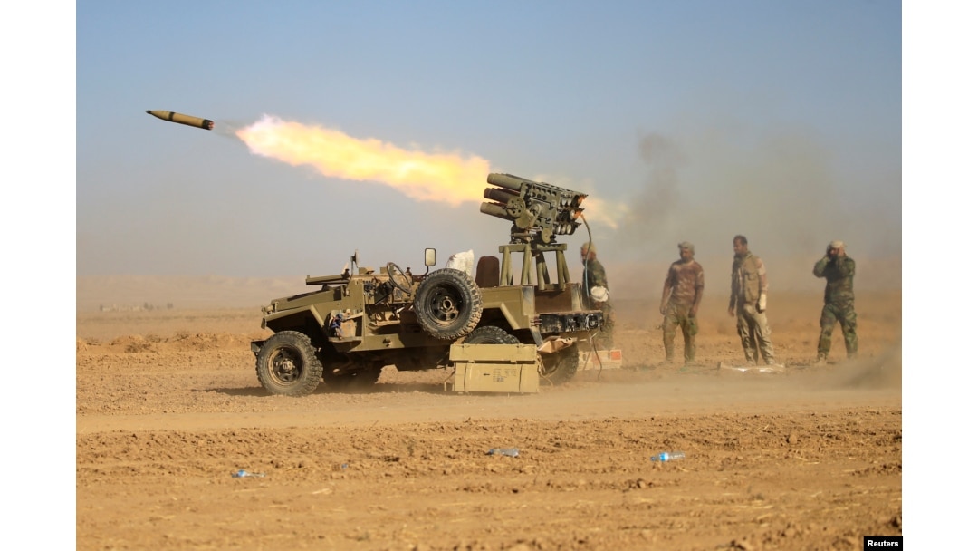 Shi'ite fighters fire a rocket toward Islamic State militants during a battle with Islamic State militants at the airport of Tal Afar west of Mosul, Iraq, Nov. 18, 2016.